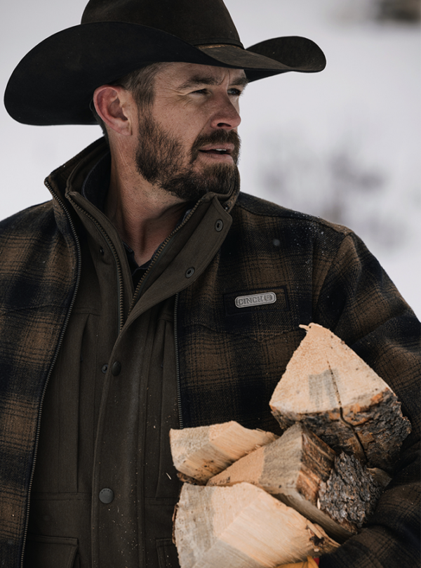 Man in plaid jacket carrying wood